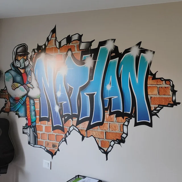 Sticker géant graffiti prénom Nathan découpé avec personnage graffeur, effet mur de briques, posé dans une chambre