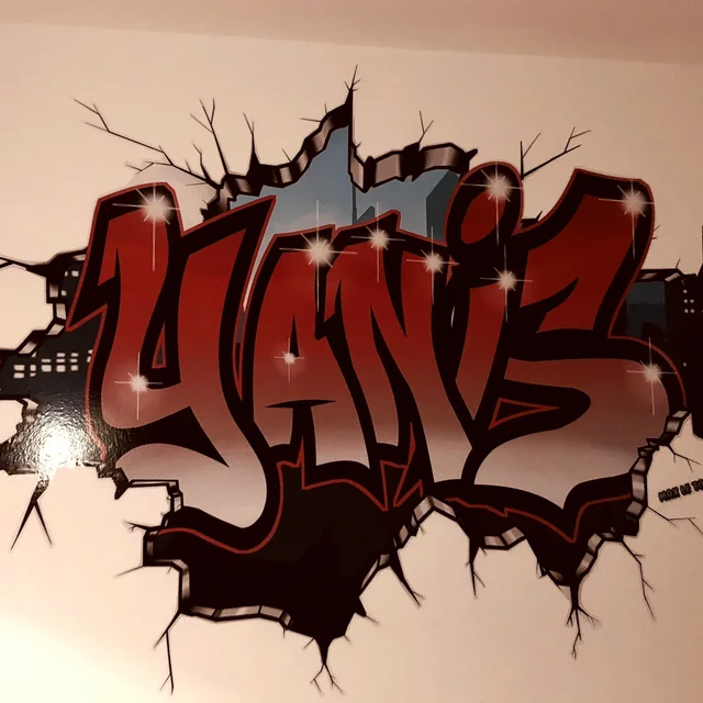 Sticker géant graffiti prénom Yanis découpé, effet mur cassé, posé dans une chambre